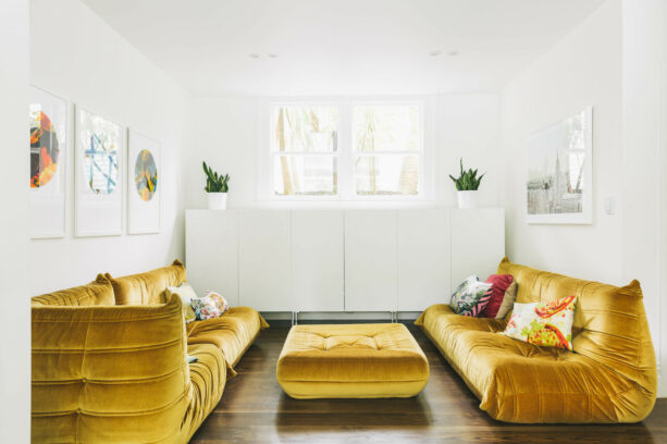gold footless couches and a table stand out in a living room with white walls