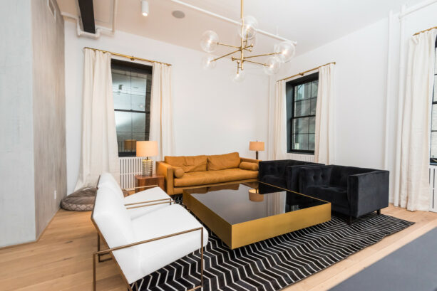 when a gold glass-top table is joined by black armchairs in an almost all white living room