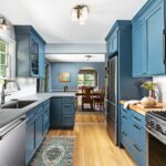 a blue peninsula with a grey countertop in a coastal galley kitchen