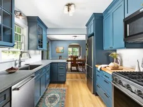 a blue peninsula with a grey countertop in a coastal galley kitchen