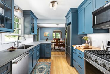 a blue peninsula with a grey countertop in a coastal galley kitchen