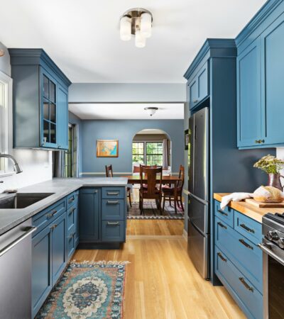 a blue peninsula with a grey countertop in a coastal galley kitchen