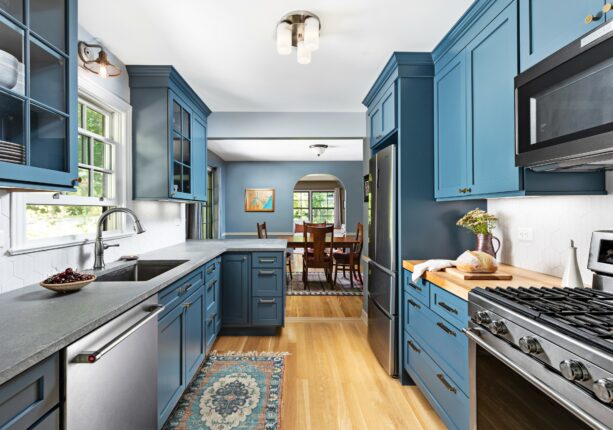 a blue peninsula with a grey countertop in a coastal galley kitchen