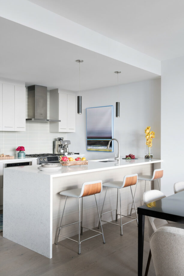 a galley kitchen with a bright peninsula and flat-panel cabinets