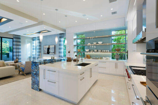 thick, long, and shiny metal shelves connect kitchen windows and a blue backsplash